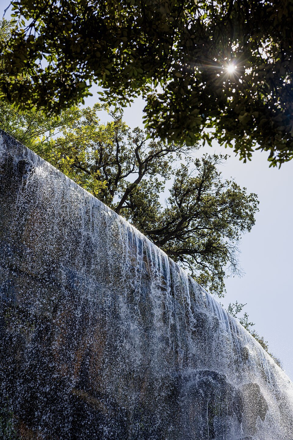 Cascade du Château viewed from below with sunburst through trees, Nice, France